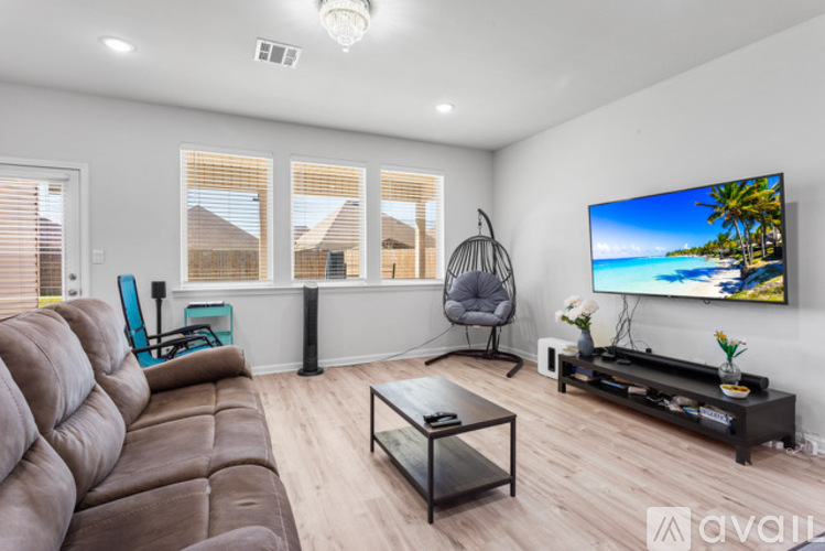 A living room with a brown couch, a television, and a chair.