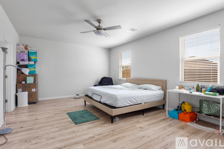 A bedroom with a bed, a fan, and a window with blinds.
