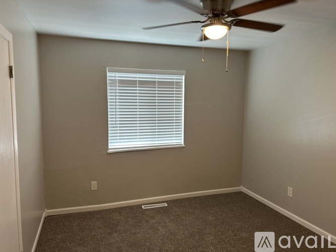 A room with a ceiling fan and a window with blinds.