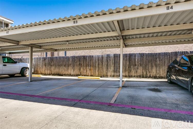 A parking lot with a white van and a black car parked under a shelter.