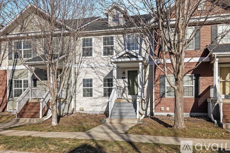 A two-story house with a front porch and a tree in front.