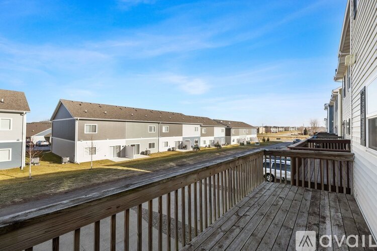 A wooden deck overlooks a parking lot with apartment buildings in the background.