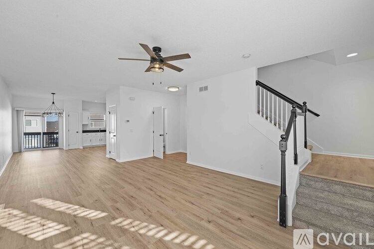 A spacious room with wooden floors and a ceiling fan.