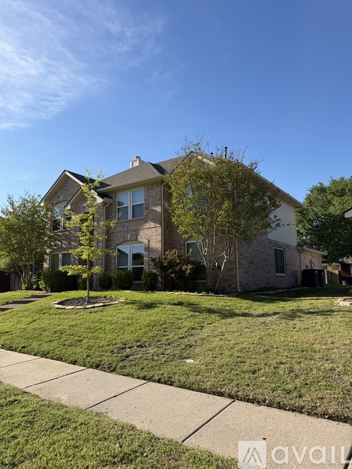 A house with a well-maintained lawn and a clear blue sky above.