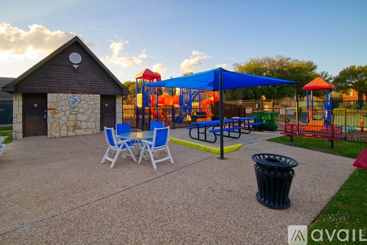 A playground with a blue canopy and a stone building.