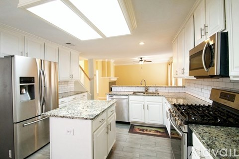 A kitchen with white cabinets and granite countertops.
