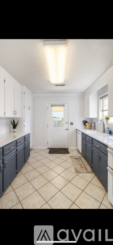 A kitchen with white cabinets and a tiled floor.