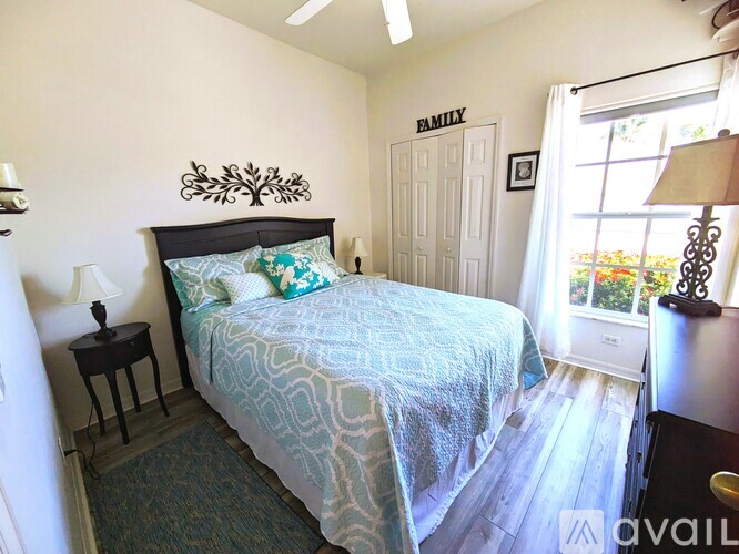 A bedroom with a bed, nightstand, and a wall decoration that says "FAMILY".