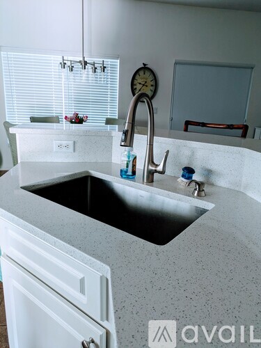 A kitchen with a sink and a clock on the wall.