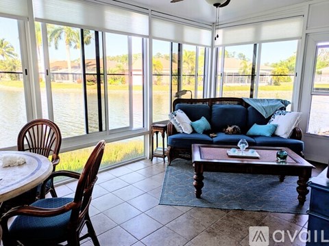 A living room with a couch, chairs, and a table with a glass on it.
