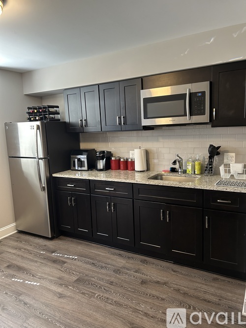 A kitchen with black cabinets and a stainless steel refrigerator.