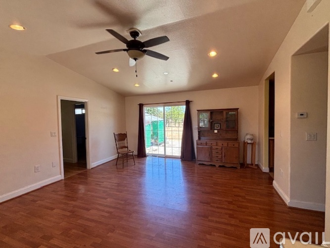A room with a ceiling fan and wooden flooring.
