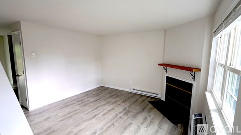 A room with a white ceiling, a window on the right, and a door on the left.