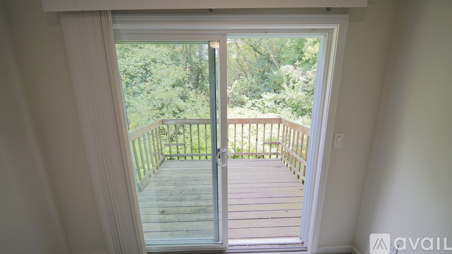 A balcony with a glass door leading to a deck surrounded by trees.
