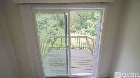 A balcony with a glass door leading to a deck surrounded by trees.