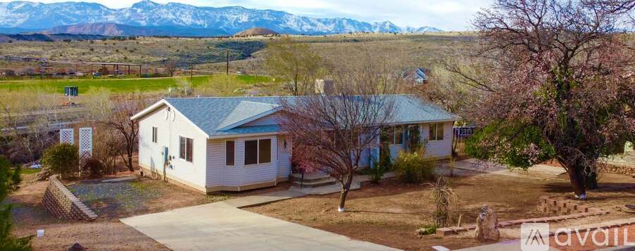 A house with a mountain range in the background and a tree in front of it.