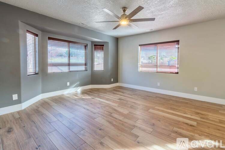 A spacious room with wooden flooring and a ceiling fan.