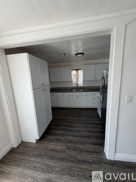 A kitchen with white cabinets and a refrigerator.