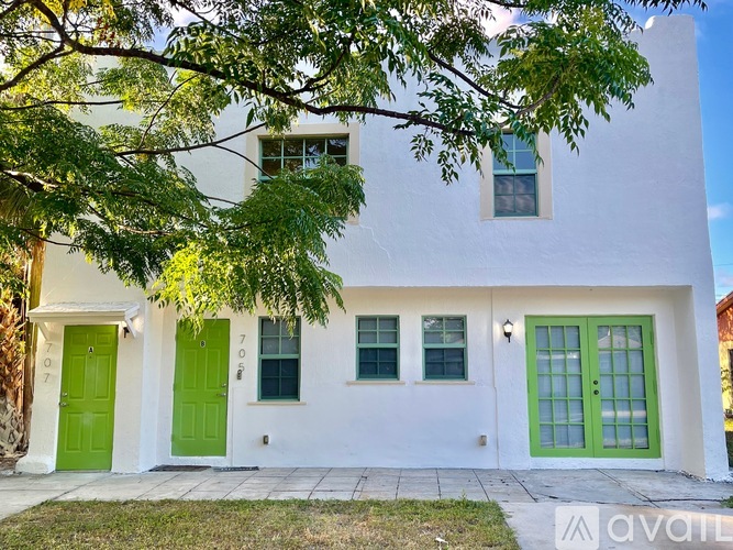 A white house with green doors and windows is for sale.