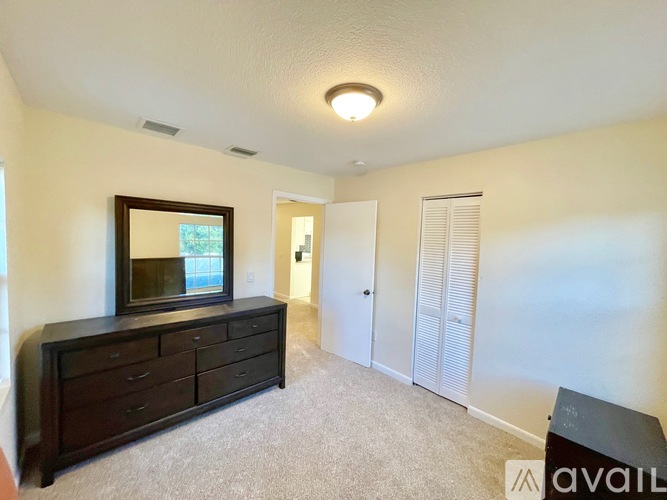 A bedroom with a large mirror and a dresser.