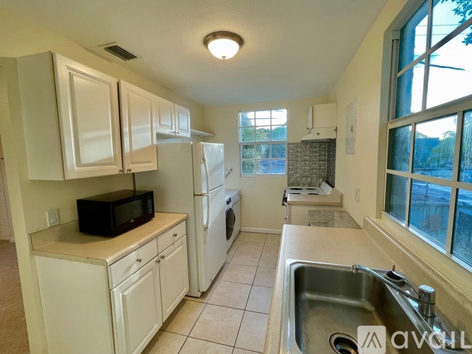 A kitchen with white cabinets and a black microwave.