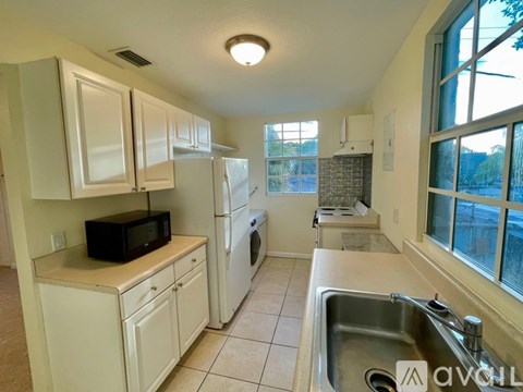 A kitchen with white cabinets and a black microwave.