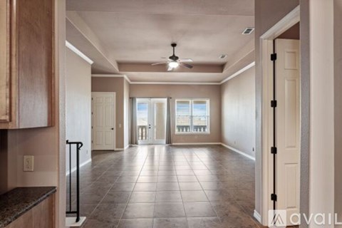 A spacious living room with a ceiling fan and sliding glass doors leading to a balcony.