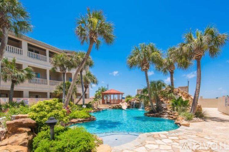 A pool surrounded by palm trees and a building in the background.