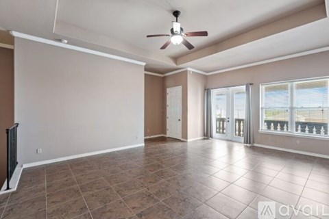 A spacious room with a ceiling fan and tiled flooring.