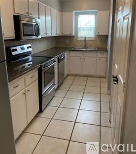 A kitchen with white cabinets and black countertops.