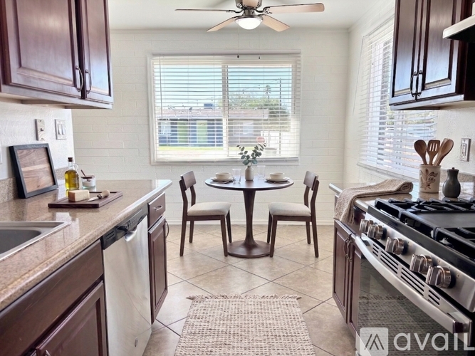 A kitchen with brown cabinets and a round table with four chairs.