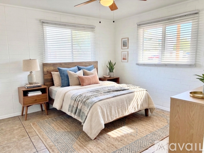 A bedroom with a bed, nightstand, and window.