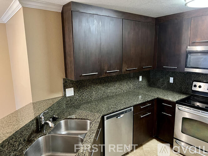 A kitchen with granite countertops and dark wood cabinets.