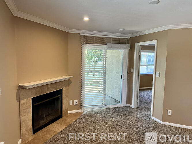 A living room with a fireplace and a carpet on the floor.