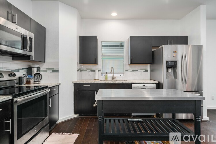 A modern kitchen with black cabinets and stainless steel appliances.