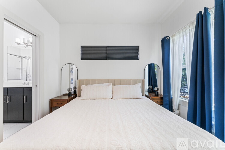 A bedroom with a large bed and a window with blue curtains.