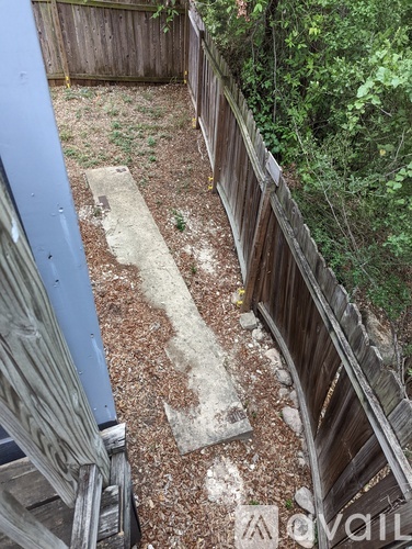 A backyard with a wooden fence and a concrete path.