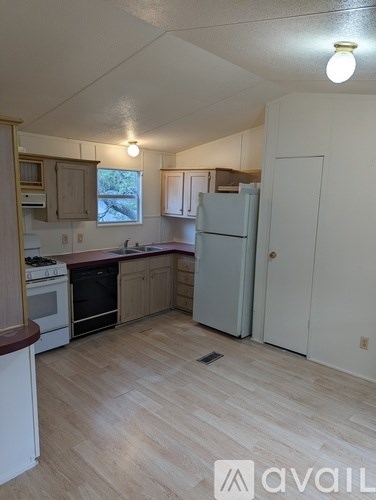 A kitchen with white appliances and wooden floors.