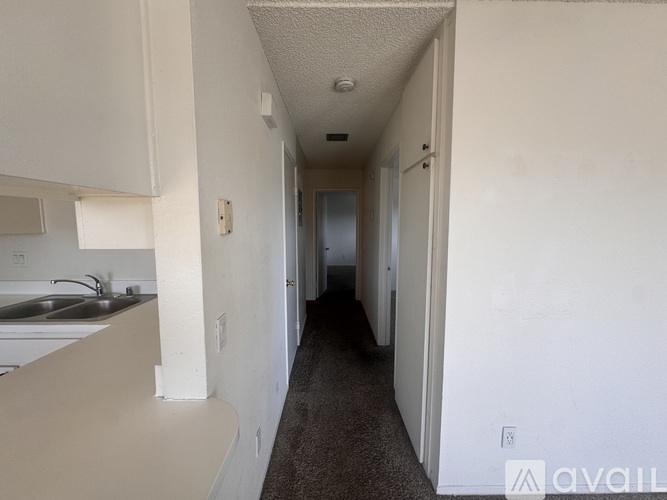 A long hallway with a carpeted floor and white walls.
