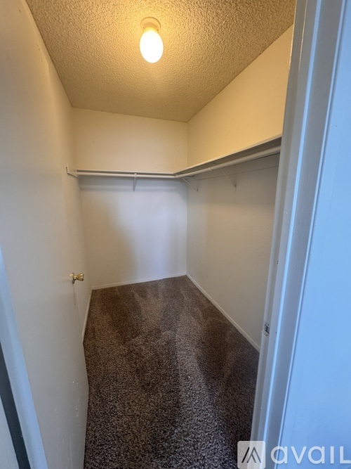 A small, empty room with a carpeted floor and a single light bulb on the ceiling.