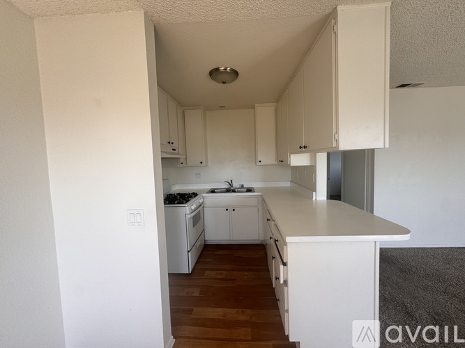 A kitchen with white cabinets and a wooden floor.