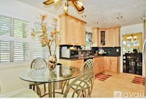 A kitchen with a table and chairs in front of a window with blinds.