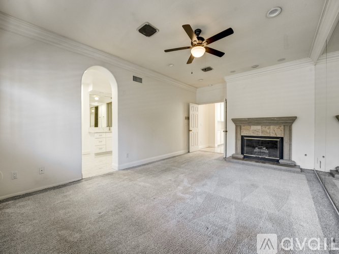 A spacious living room with a fireplace and a ceiling fan.