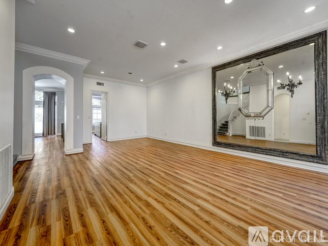 A spacious room with wooden floors and a large mirror on the wall.