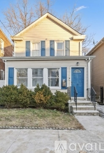 A yellow house with a blue door and windows.