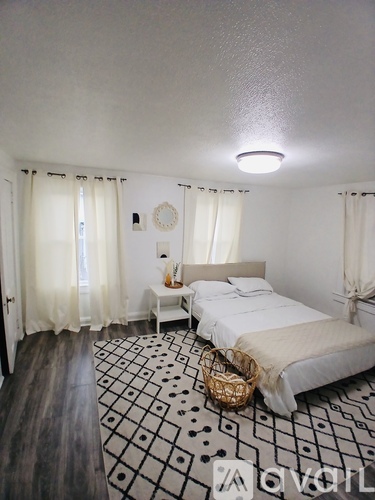 A bedroom with a large bed and a basket on the floor.