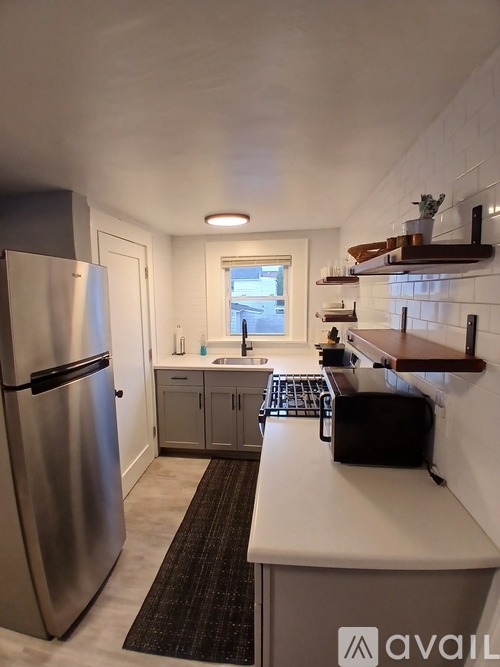 A kitchen with a stainless steel refrigerator and a black and white checkered rug.