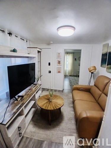 A living room with a brown leather couch and a flat screen TV.
