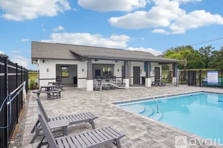 A pool area with a building and picnic tables.