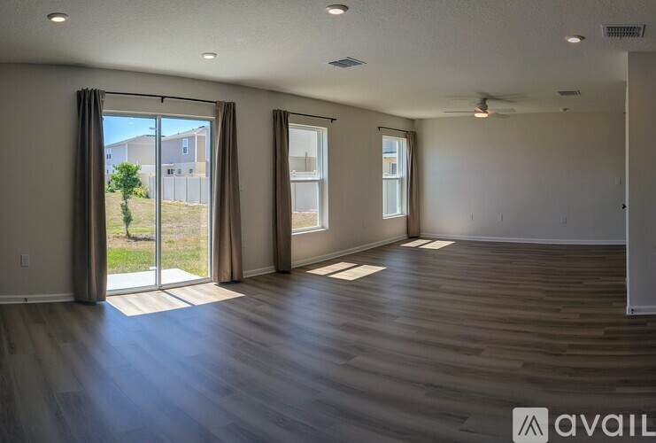A spacious room with wooden floors and large windows.